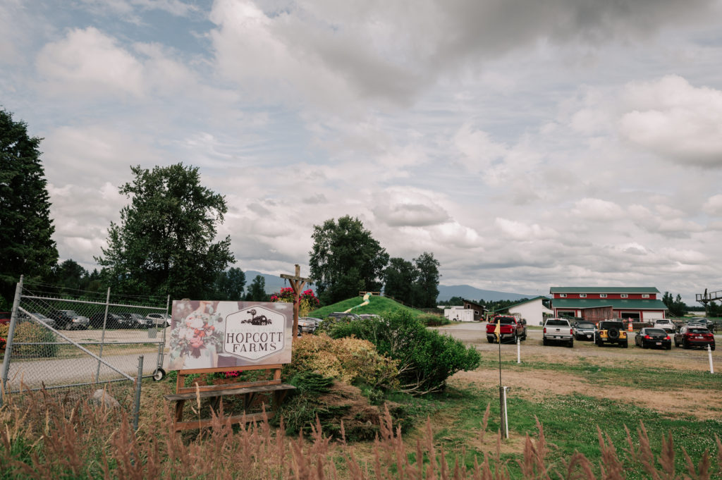 The Hopcott Farms sign at the country road entrance with the big red barn in the background.
